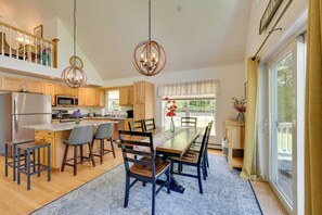 Une cuisine moderne avec des meubles en bois, un îlot central, des tabourets de bar et un lustre.