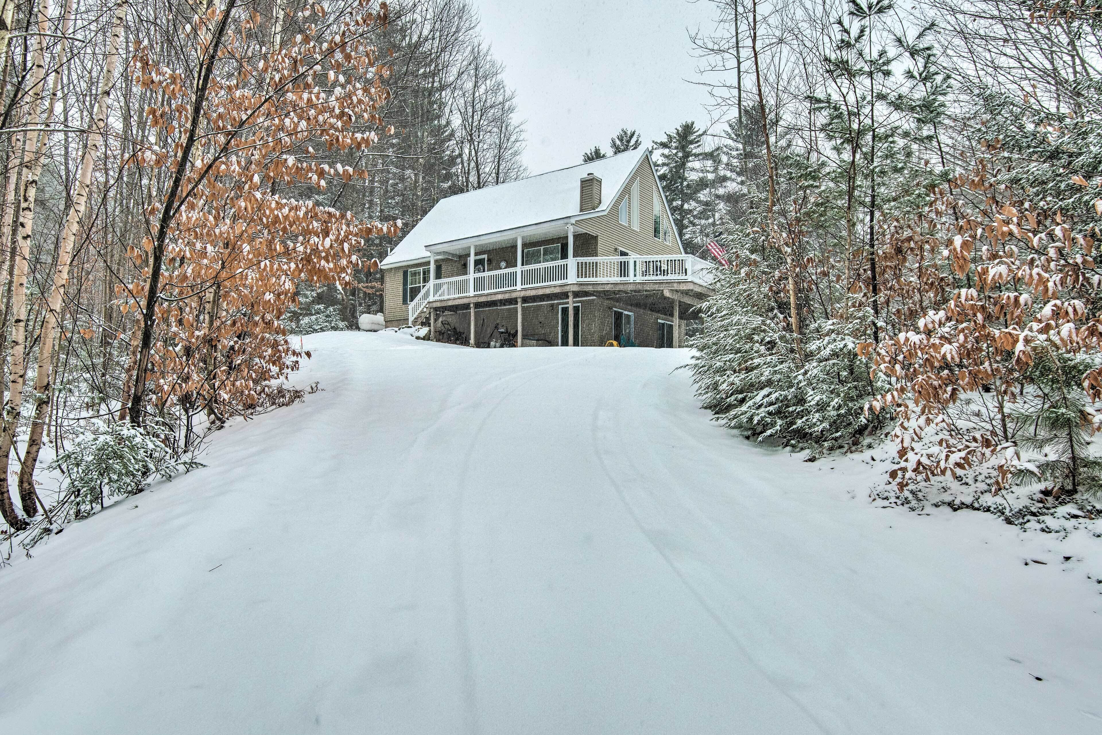 A two-story house with a balcony, surrounded by snow-covered trees.