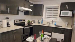 Una cocina moderna con armarios oscuros, una isla central y un comedor preparado para cuatro.