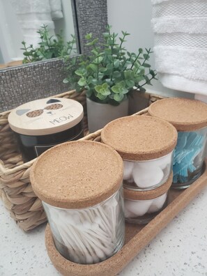 A tray with three jars, one with a cork lid and cotton swabs, another with a cork lid and a white substance, and a third with a cork lid and blue cotton swabs. - Lux Modern 2bd Radiant Suite+Free Parking (Delta)