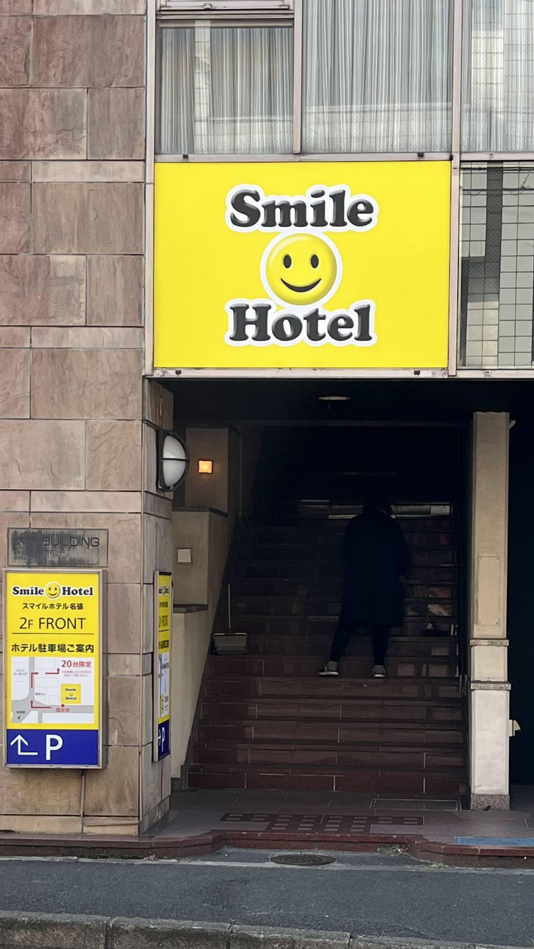 A yellow sign for Smile Hotel with a smiley face logo.