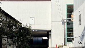 A hotel entrance with a covered driveway and a building with a green door. - Smile Hotel Nabari (Nabari)