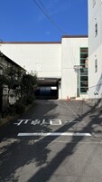 Entrada de un hotel con un camino cubierto y un edificio con puerta verde.