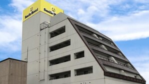 A building with a distinctive triangular roof and a yellow sign reading "Smile Hotel" at the top. - Smile Hotel Nabari (Nabari)
