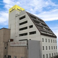 Un edificio con un techo triangular característico y un letrero amarillo que dice "Smile Hotel" en la parte superior.