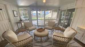 A sunroom with wicker furniture, a patterned rug, and a view of the outside. - Canal Front with Dock & Golf Cart, Family Friendly in South Litchfield (Pawleys Island)