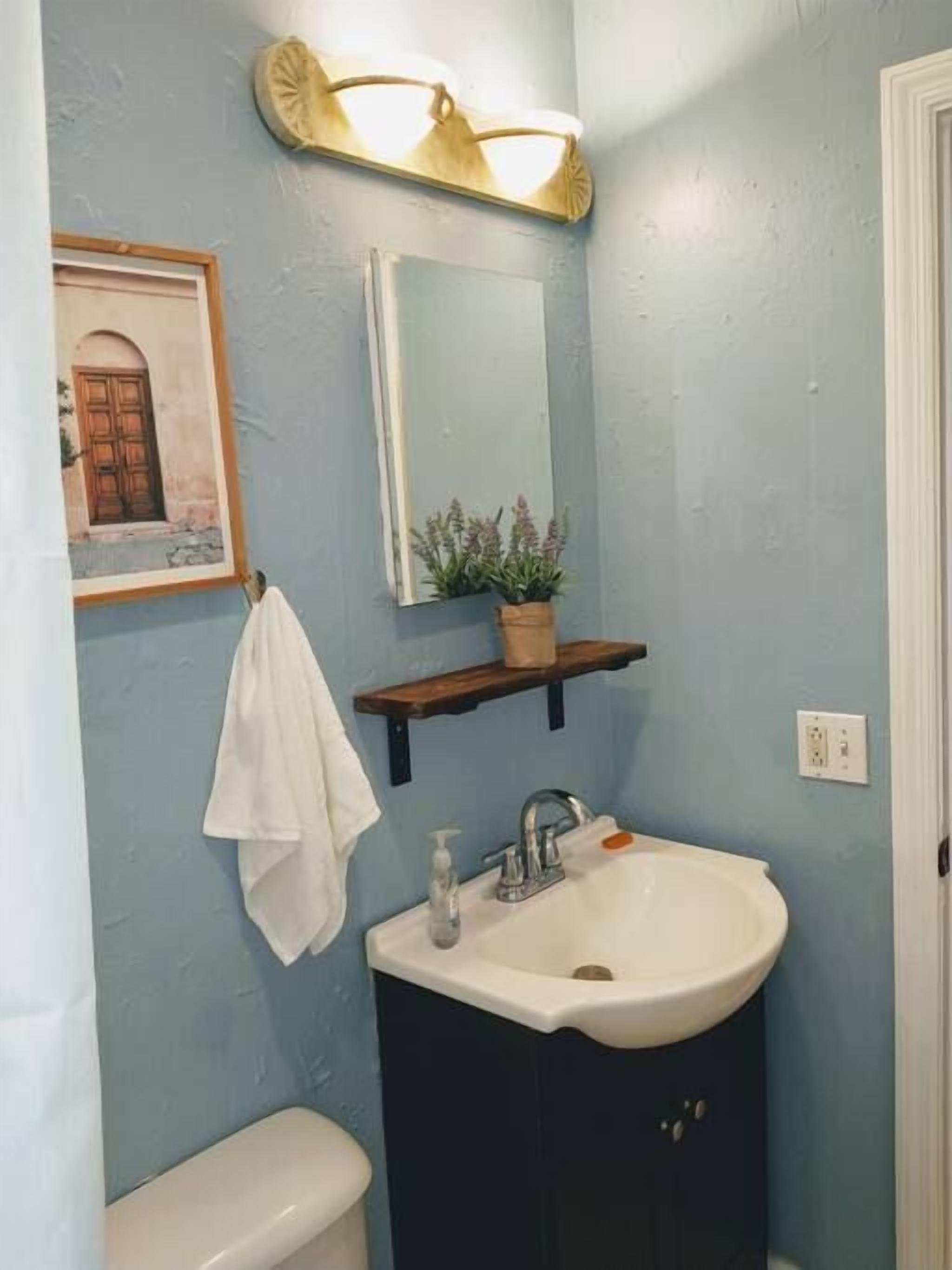 A bathroom with a sink, mirror, and towel rack.
