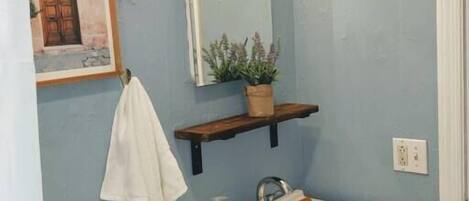 A bathroom with a sink, mirror, and towel rack.