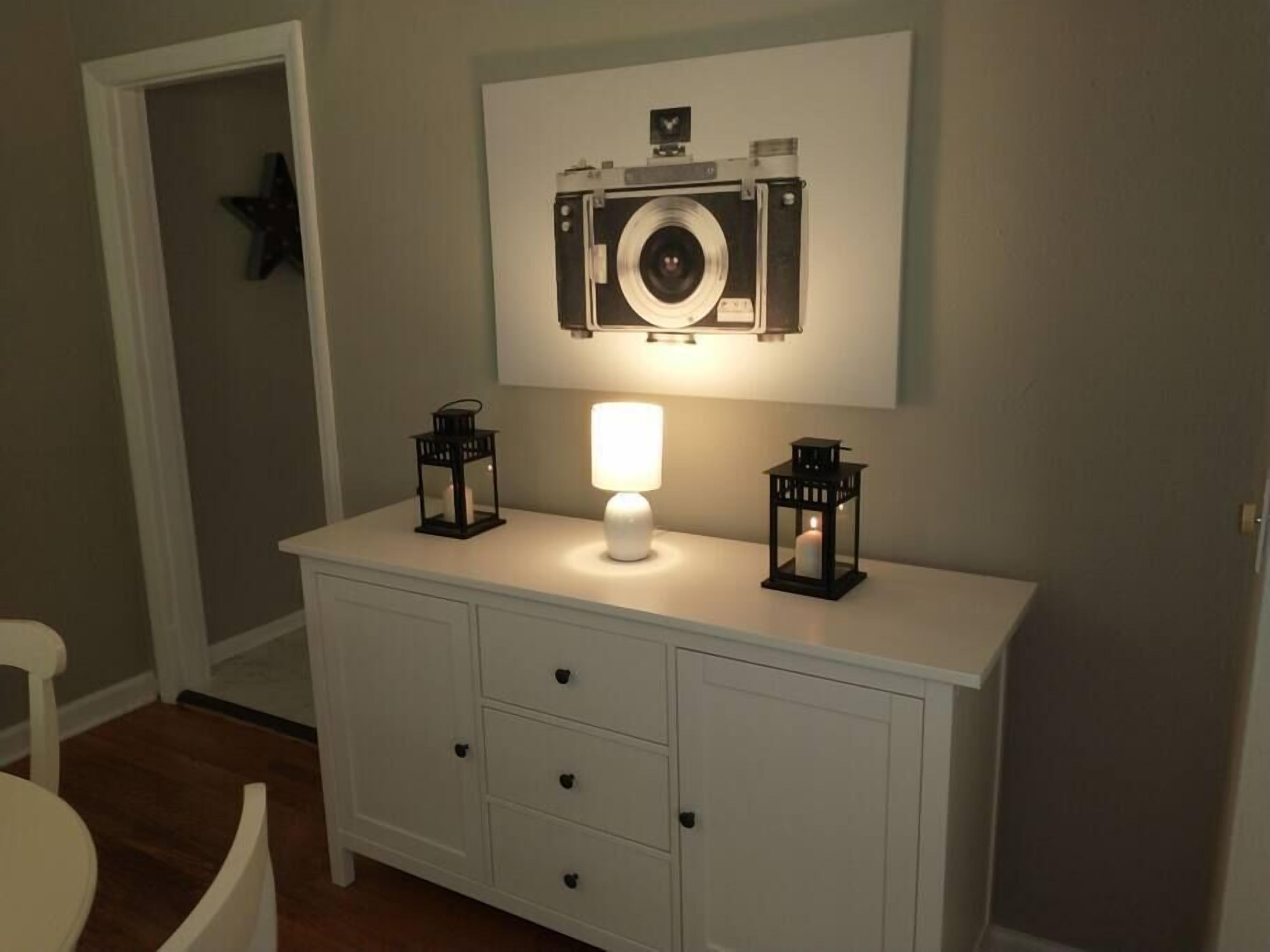 A white dresser with two black lanterns and a white lamp on top.