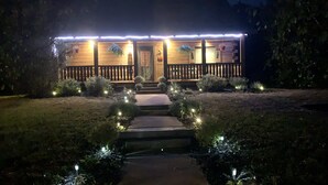 Une maison dotée d’une terrasse en bois, d’un porche à l’avant et d’un chemin menant à l’entrée.