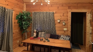 Un intérieur en bois comprenant une table à manger, des chaises, un rideau à motifs et un luminaire au plafond.