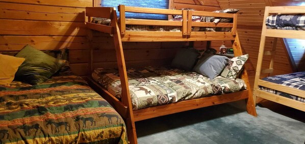 A cozy cabin room with a bunk bed, a patterned bedspread, and a window with blinds. - Beautiful and cozy Cabin (Warrens)