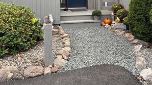 A modern house with a dark blue front door, a small porch, and a gravel driveway.