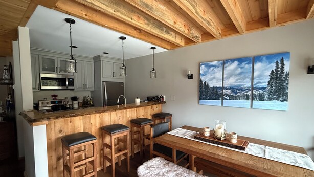 A kitchen with wooden bar stools, a wooden dining table, and a bench.
