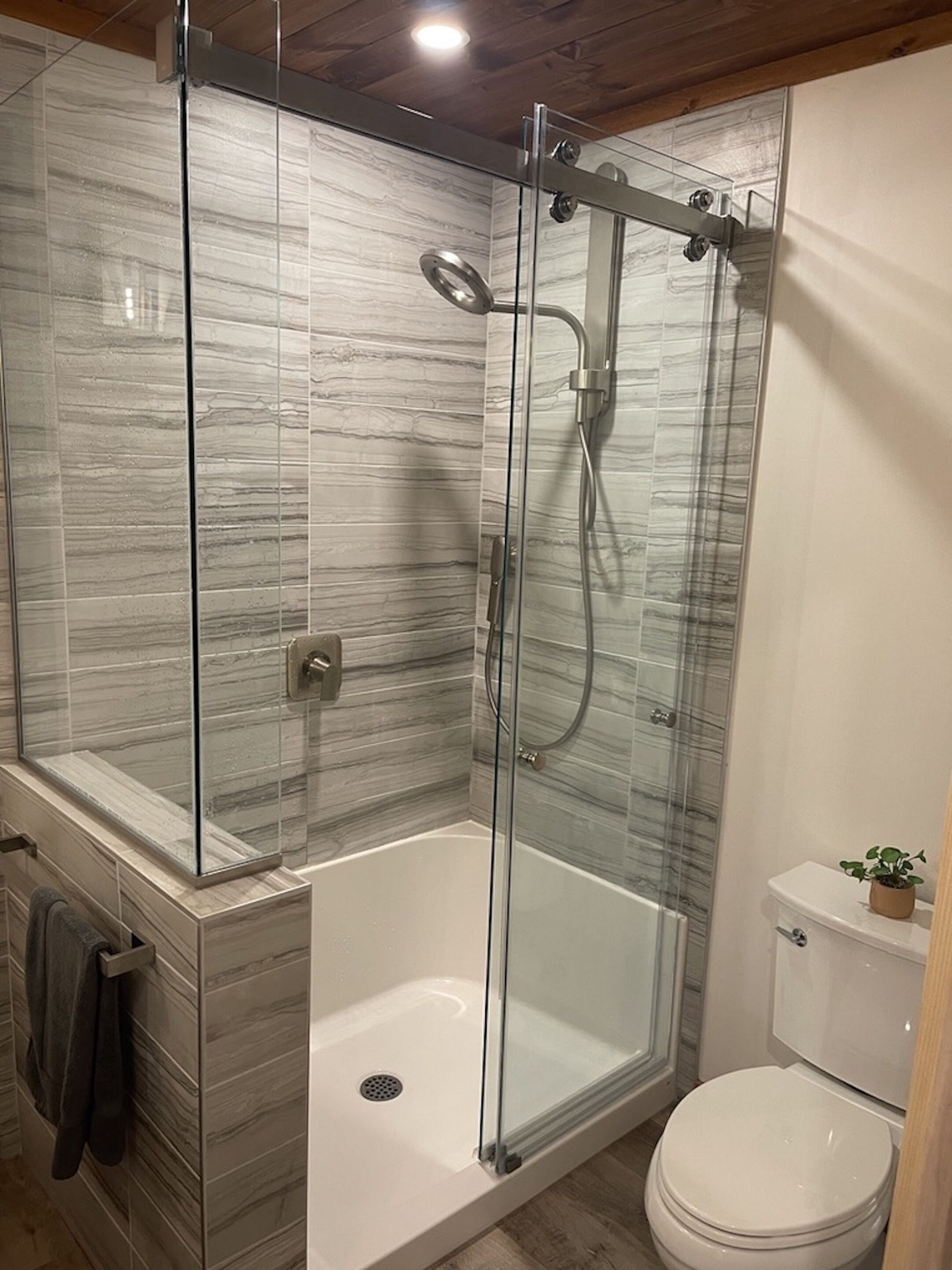 A modern bathroom with a glass-enclosed shower, a separate bathtub, and a toilet.