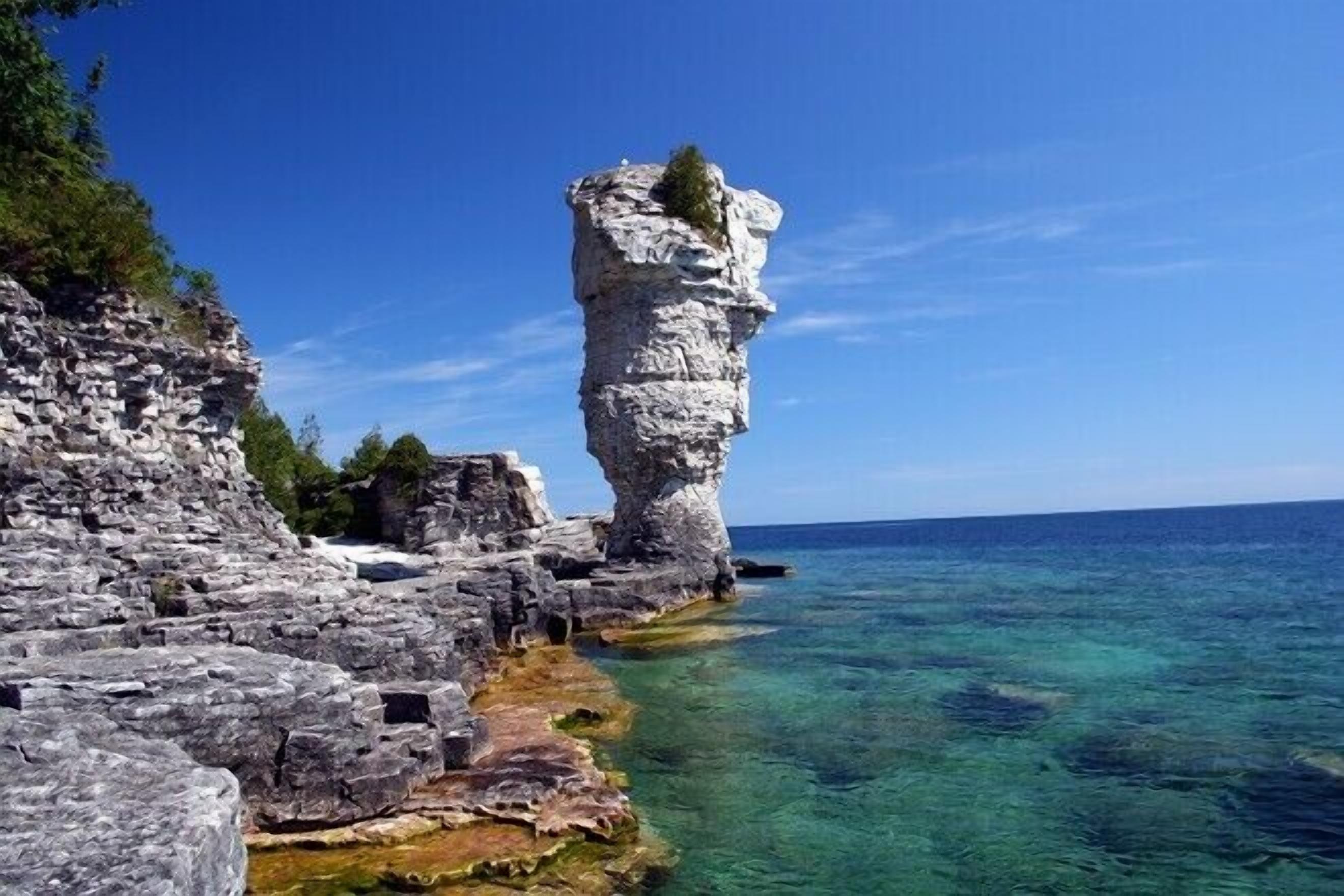 Eine Küstenfelsformation mit klarem Wasser und blauem Himmel.