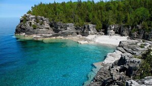 Een kustlandschap met helder turquoise water, rotskliffen en dicht bos.