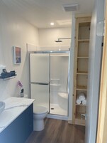 Un baño moderno con ducha acristalada, inodoro y tocador con encimera de mármol.