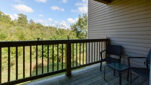 A wooden deck with a railing, two chairs, and a view of a forested area. - Abi's Place, No Stairs! Central Location!  Stylish!  3 BDRM 2 BA, Pool Available (Branson)
