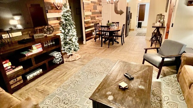 A living room with a ceiling fan, a TV, a Christmas tree, a coffee table, and a patterned rug. - Abi's Place, No Stairs! Central Location!  Stylish!  3 BDRM 2 BA, Pool Available (Branson)