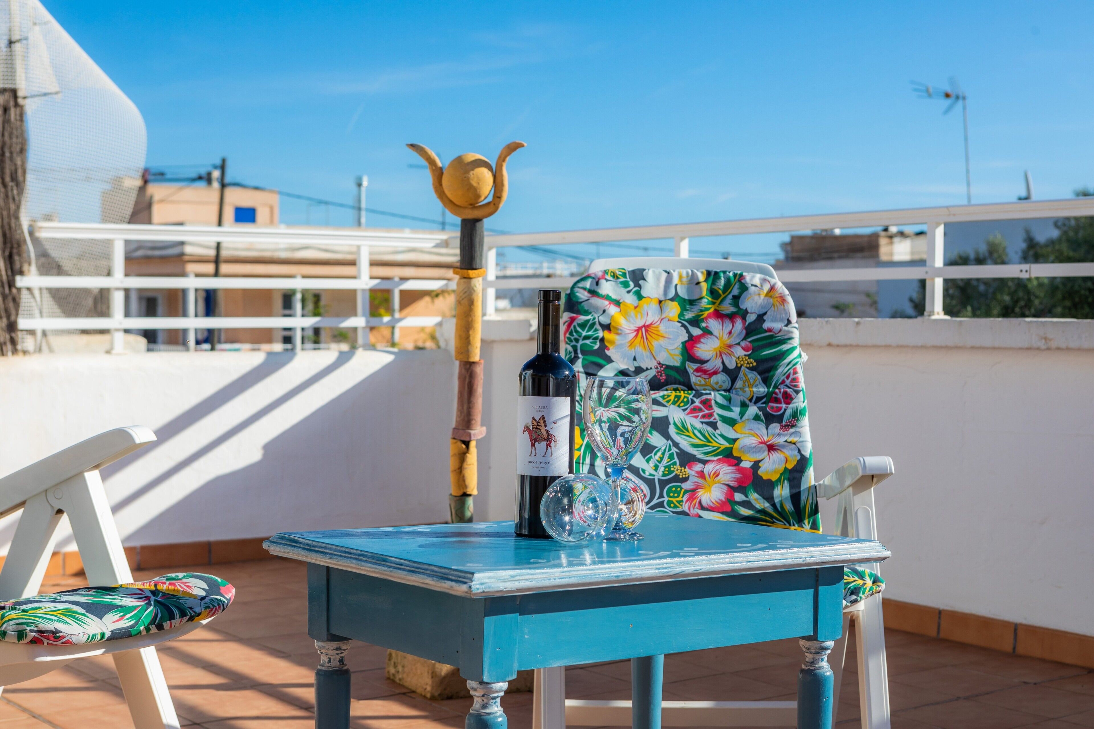 A blue table with a chair, a bottle, and a decorative item on a balcony.