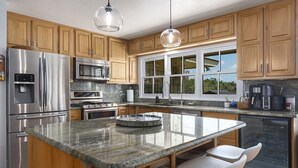 A modern kitchen with wooden cabinets, stainless steel appliances, a granite countertop, and a large window. - Landhaus Eichenbaum | Pool | Hot Tub (Fredericksburg)