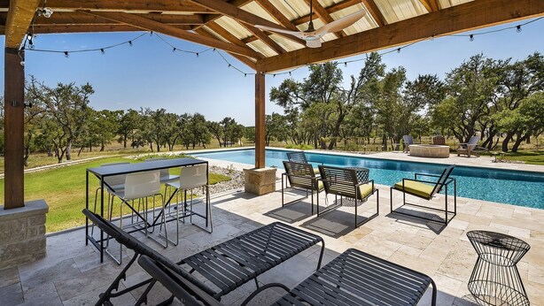 A covered outdoor area with a pool, lounge chairs, and string lights. - Landhaus Eichenbaum | Pool | Hot Tub (Fredericksburg)