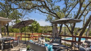 An outdoor patio with a pool, covered seating, and string lights. - Landhaus Eichenbaum | Pool | Hot Tub (Fredericksburg)