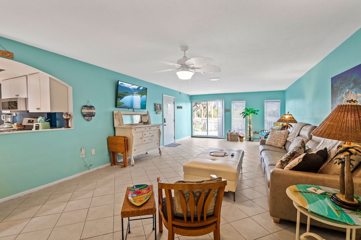 A spacious living area with a kitchen, a dining table, a sofa, and a ceiling fan.