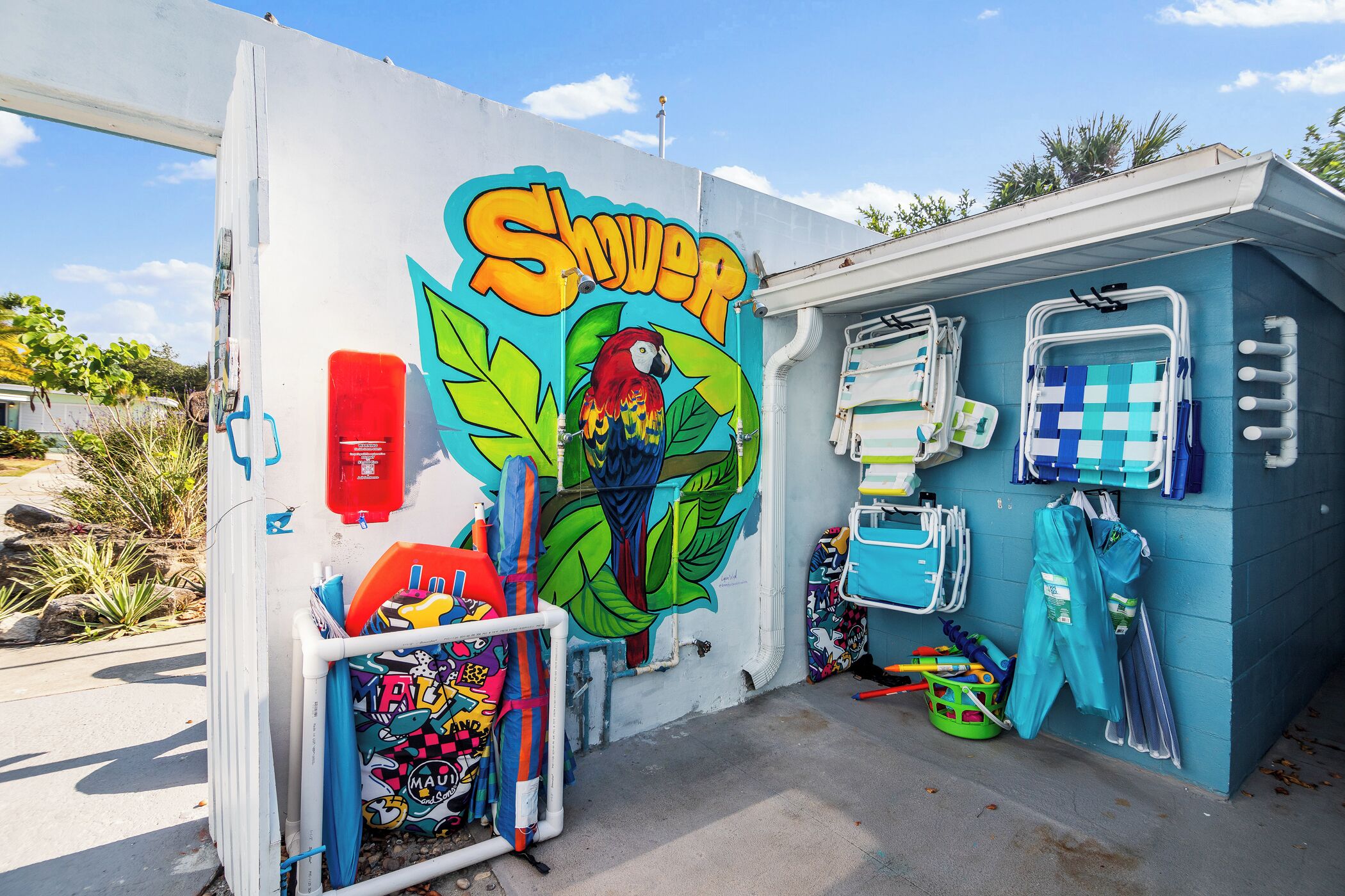 A shower area with a colorful mural, a red fire extinguisher, and various cleaning supplies.