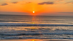 Ein Strand mit Sonnenuntergang über dem Ozean, der eine ruhige und friedliche Atmosphäre schafft.
