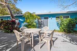 A blue building with a patio area featuring a round table and four chairs.