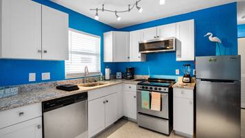 A modern kitchen with white cabinets, a stainless steel refrigerator, and a blue accent wall.