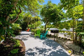 A pathway lined with green chairs, surrounded by lush trees and plants.