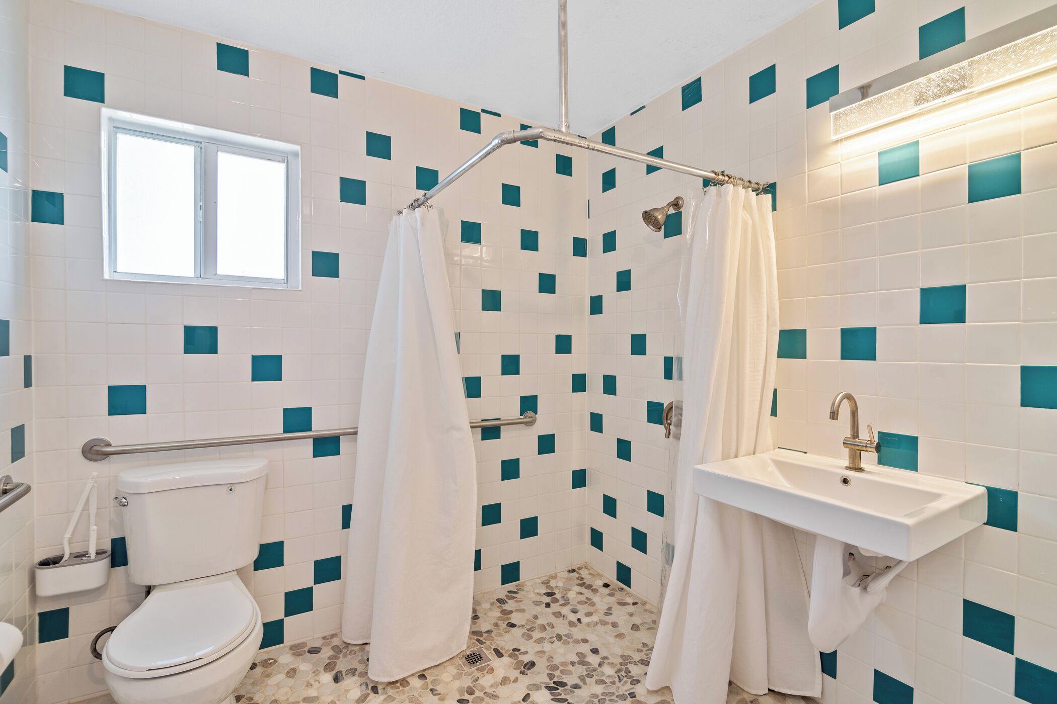 A bathroom with a toilet, shower, and sink.