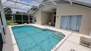 Une piscine intérieure couverte avec un toit en verre, un espace patio aménagé avec des sièges et une vue sur le paysage environnant.