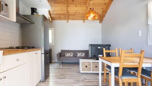 A compact kitchen with a wooden ceiling, a dining area with a table and chairs, and a sofa in the background. - Vacation home Jorge by Interhome (El Rosario)