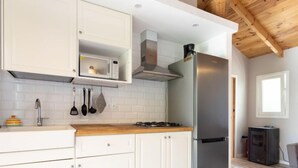 A modern kitchen with white cabinetry, a stainless steel refrigerator, a built-in microwave, and a gas stove. - Vacation home Jorge by Interhome (El Rosario)