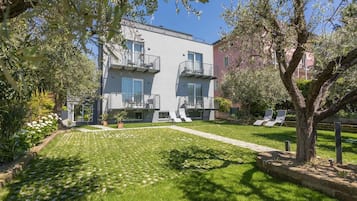 Un edificio moderno con balconi, un prato curato e posti a sedere all'aperto.