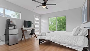 Une chambre moderne équipée d’un lit, d’un bureau, d’une télévision et d’un ventilateur de plafond.