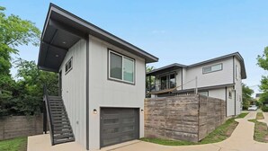 Une maison moderne à deux étages, dotée d’un garage, d’un escalier et d’une clôture en bois.