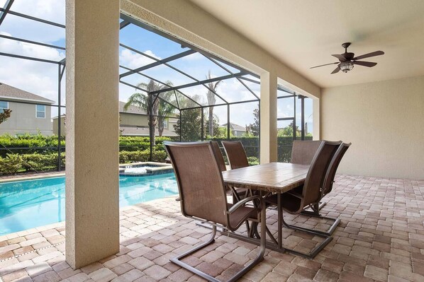 A covered patio with a pool, outdoor seating, and a ceiling fan. - Encore 7BR Villa, Pool, Near Disney (Kissimmee)