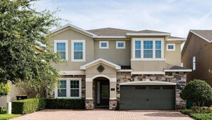 A two-story house with a stone facade, a garage, and a well-maintained front yard. - Cheery Villa with Games Room at Encore (Kissimmee)