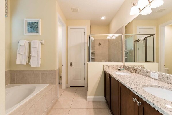 A modern bathroom with a bathtub, a large vanity with a sink, and a glass shower enclosure.