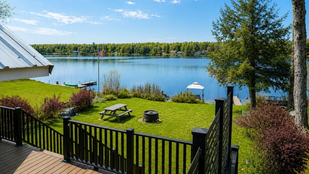 En fastighet vid sjön med en terrass, ett picknickbord och en flagga.