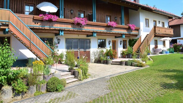 En traditionell chalet med träbalkonger, en stenlagd gång och en välskött trädgård.
