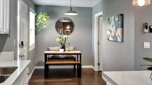 Een moderne keuken met een houten bankje, een ronde spiegel en een hanglamp.