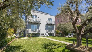 A modern building with balconies, a well-maintained lawn, and outdoor seating.