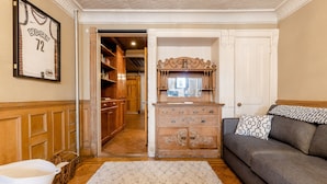 A living room with a gray sofa, a wooden cabinet, and a framed sports jersey on the wall. - 1899 Historic Luxury Brooklyn Brownstone (Brooklyn)