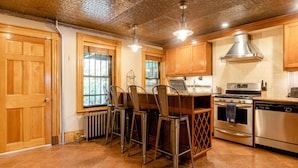 A kitchen with wooden cabinets, a central island with bar stools, stainless steel appliances, and a decorative ceiling. - 1899 Historic Luxury Brooklyn Brownstone (Brooklyn)